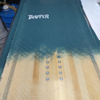 Custom power and carving snowboard with teal resin tint on wood grain